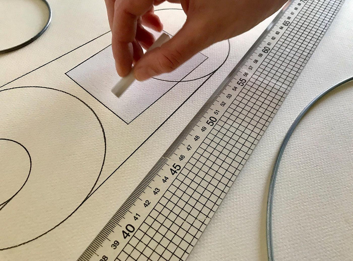 Close-up of Alarah Gee using a white drawing stick beside a ruler and geometric outlines on paper