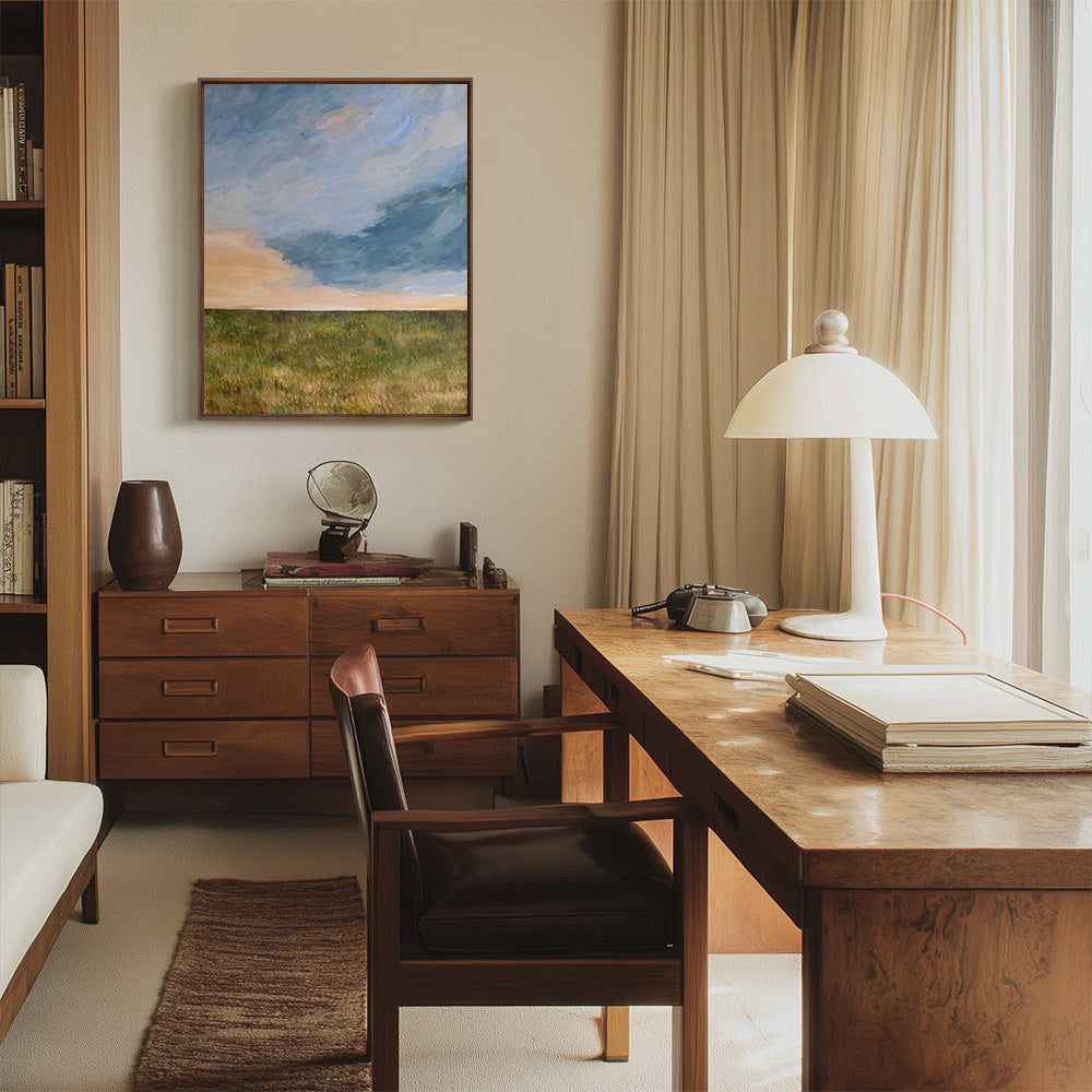 An office scene with a vertical landscape painting titled A Field at Sunset hanging above a wooden credenza and a desk