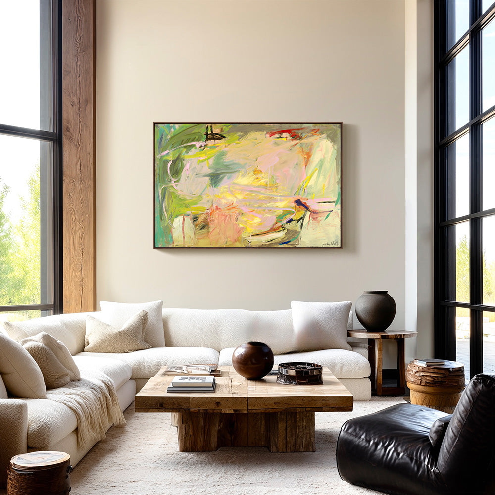 Abstract painting hangs above a white sectional sofa in a sunlit room with floor-to-ceiling windows