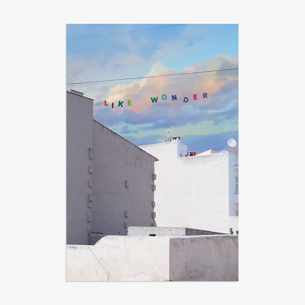 Like Wonder print by James Needham White buildings under a blue and pink cloudy sky with LIKE WONDER in colorful