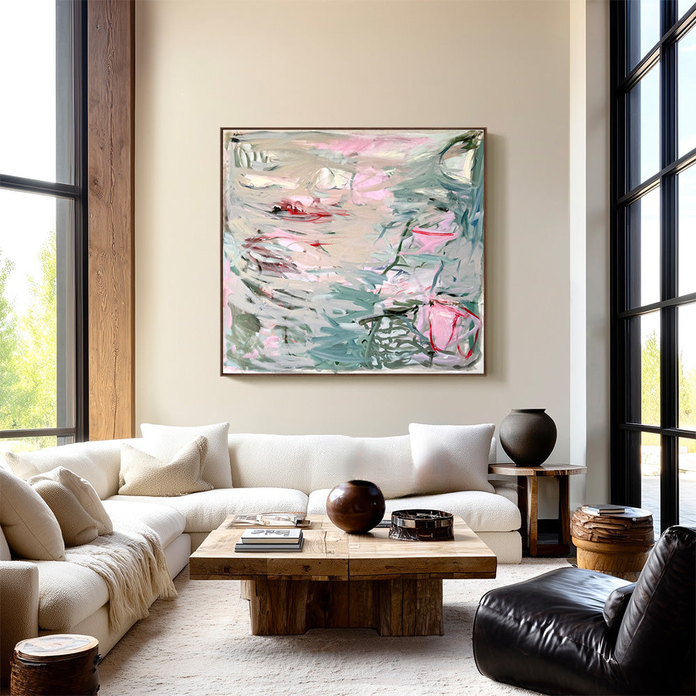Abstract painting with soft pink and sage green palette displayed on a beige wall above a white sectional sofa