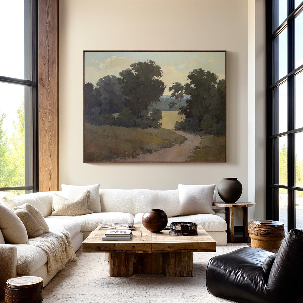 Original 60x77 landscape painting "Quiet Process" by Ashley Ozmint. Trees in field with a dirt path and a cloudy sky. Painting in modern living room.