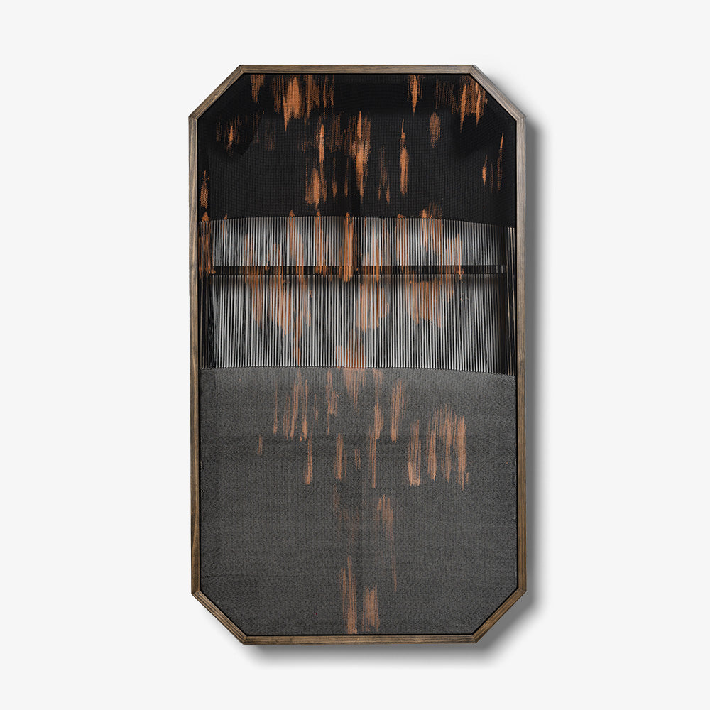 Octagonal textile art with black and orange abstract vertical thread patterns in a dark wooden frame