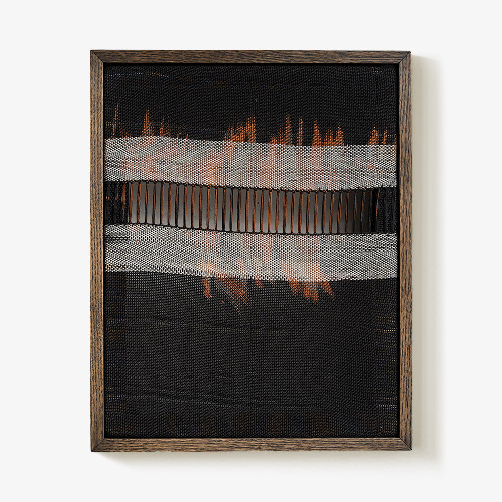 Black textile wall hanging featuring a central open-weave section and rust-colored accents in a dark wood frame