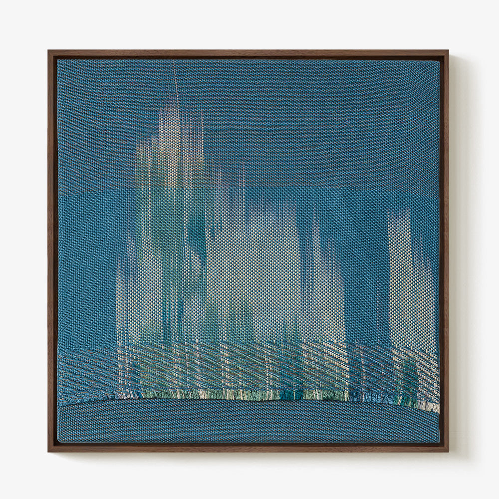 Square blue textile art in a brown wooden frame featuring light vertical streaks and a distinct horizontal lower band
