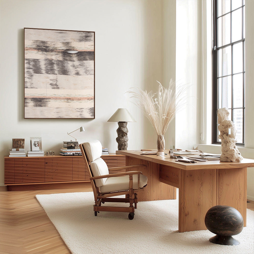 Office interior with beige gray and peach textile wall art hung above a long wooden credenza with decor items