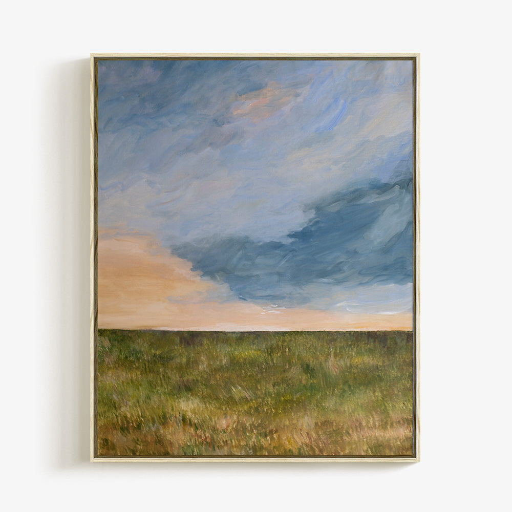 Vertical landscape painting titled A Field at Sunset in a light wood frame with a blue and orange sky over a green field
