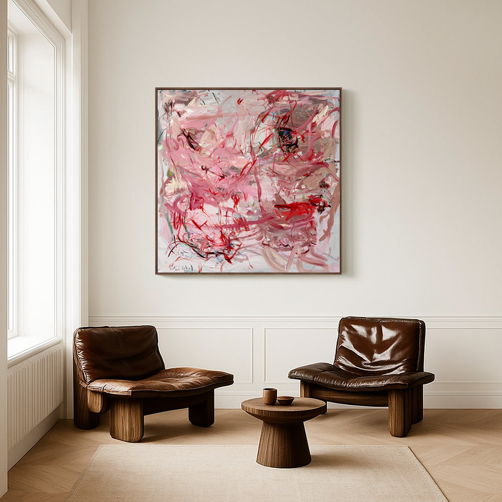 An abstract pink and red painting hanging above two brown leather armchairs and a small wooden side table