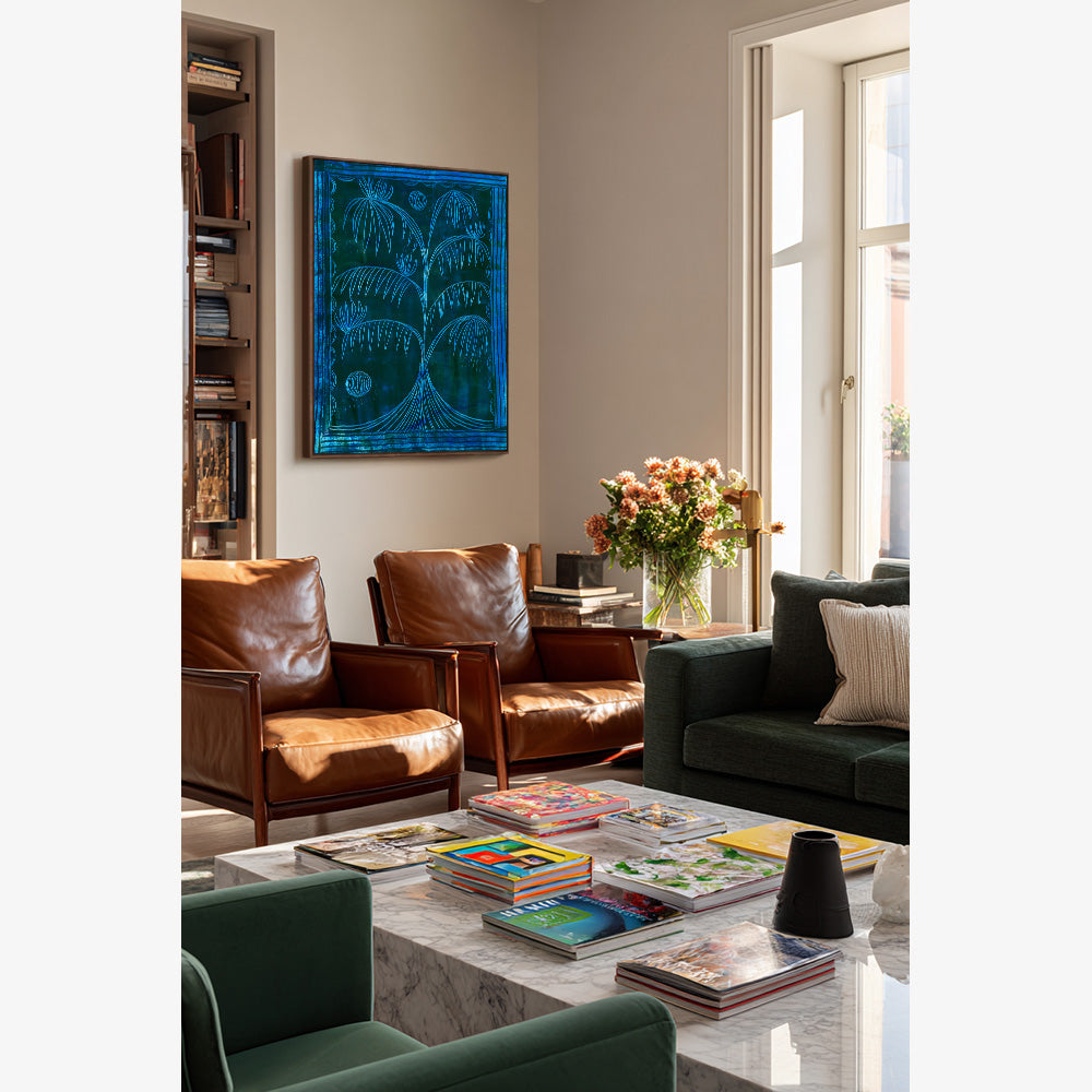 Vertical painting of a blue palm tree on dark teal hanging above a marble coffee table in a living room