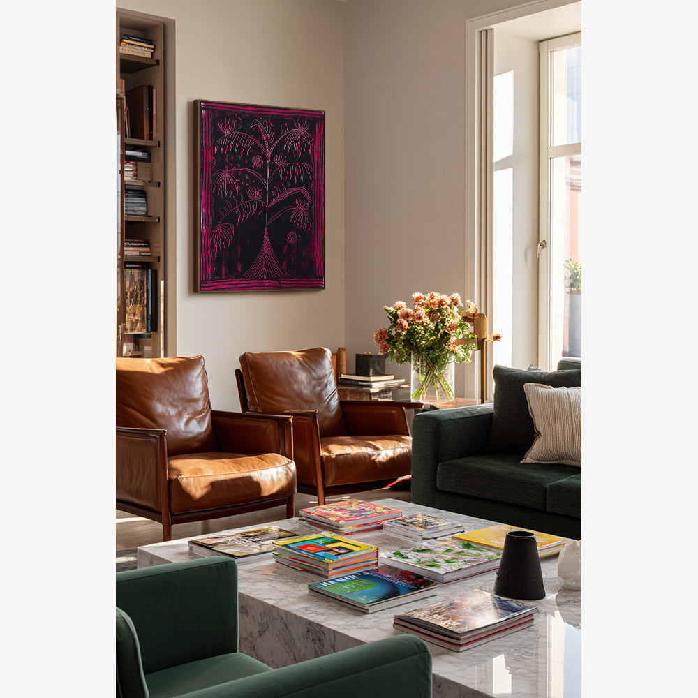 Painting of a dark-toned stylized tree with magenta linework displayed above two tan leather armchairs