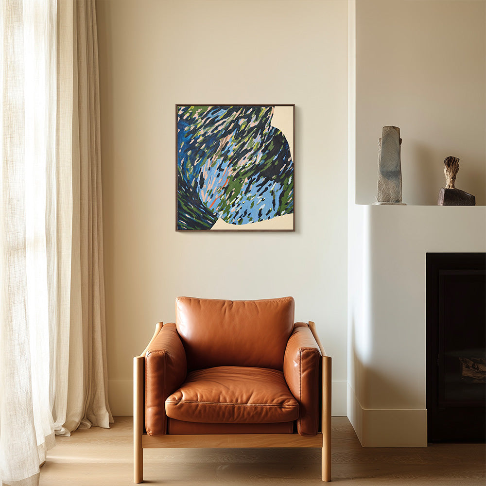 Framed abstract painting in blue and green hanging on a neutral wall above a brown leather armchair