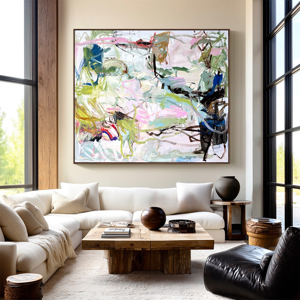 Large abstract painting with lively colorful strokes hung over a modern sofa in a bright contemporary living space