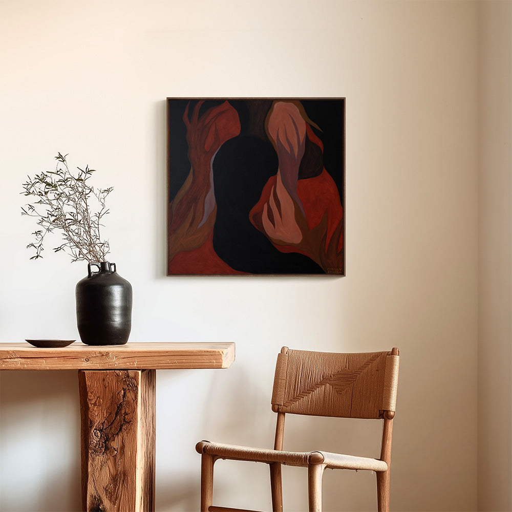 Framed painting hanging on a neutral wall above a wooden table with a black vase and a wooden chair