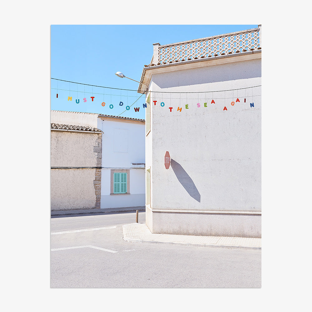 Unframed vertical photo print featuring white stucco buildings with a green shutter and colorful bunting