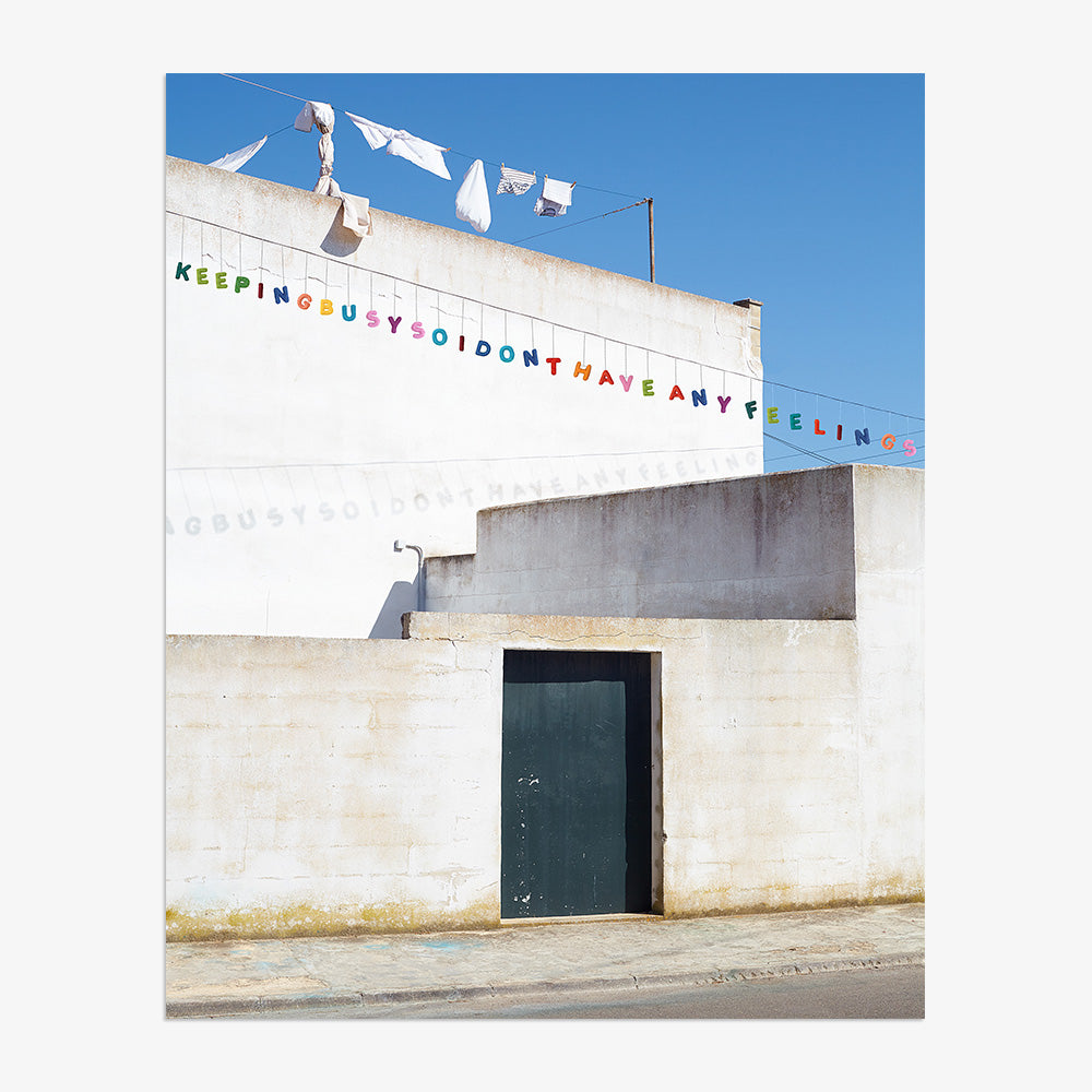 A white building facade with a green door and bunting text suspended above