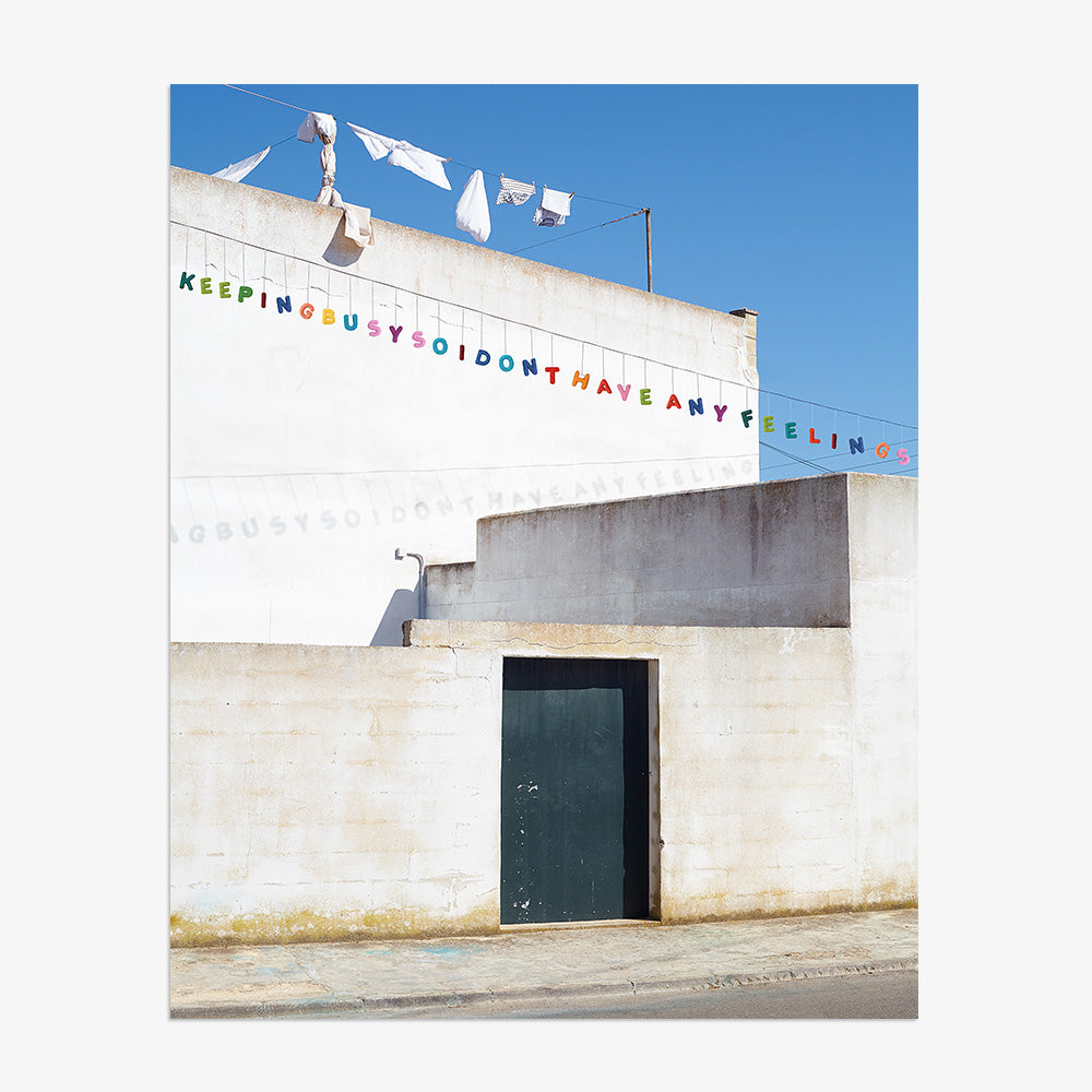 Architectural print of a white building with a dark blue door and a colorful text banner