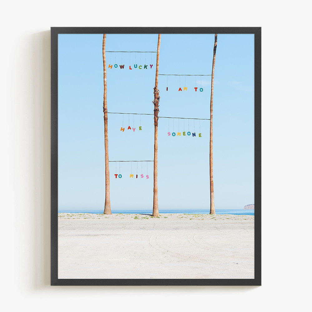 Framed print of three palm trees on a beach with the ocean in the background text reading HOW LUCKY I AM TO HAVE