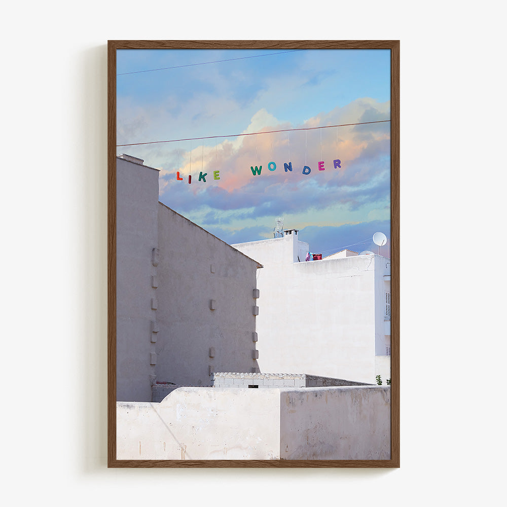 Like Wonder print by James Needham in a dark wood frame White buildings under a blue and pink cloudy sky with LIKE