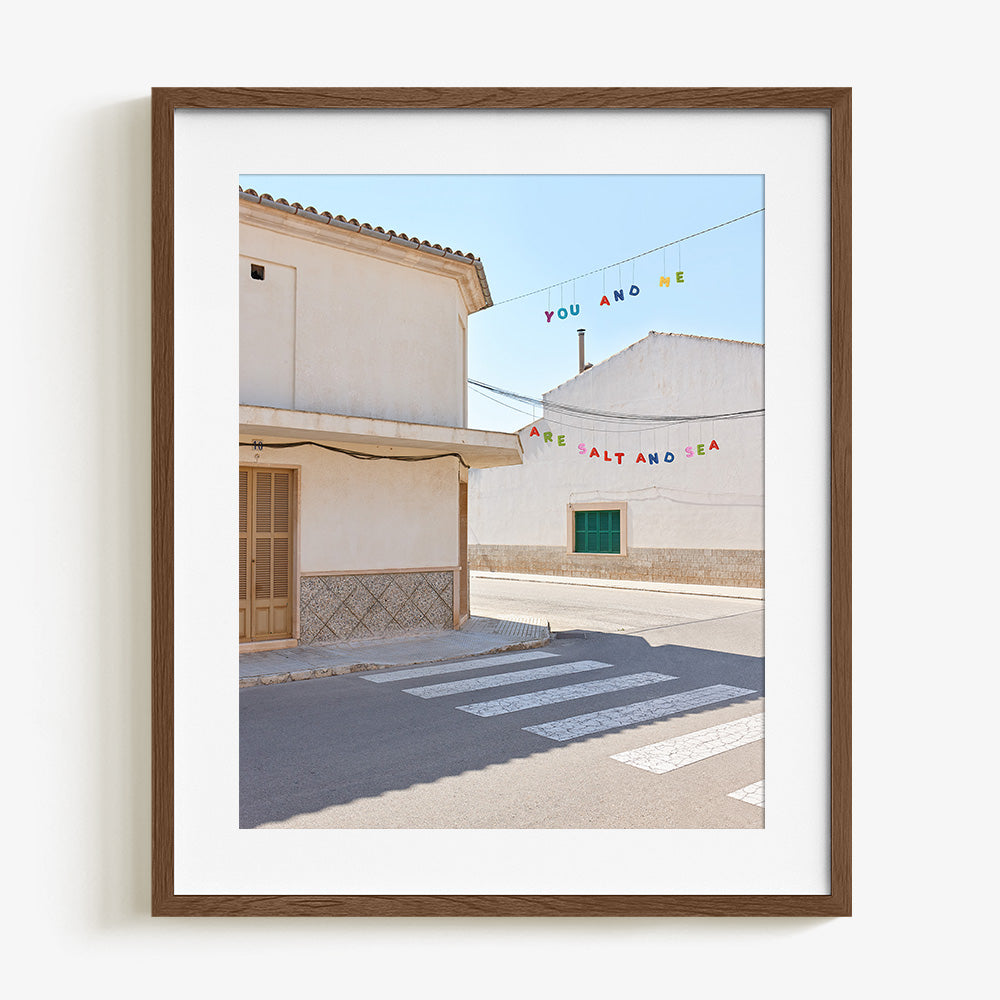 Street scene with white buildings a crosswalk and colorful hanging text in a walnut wood frame
