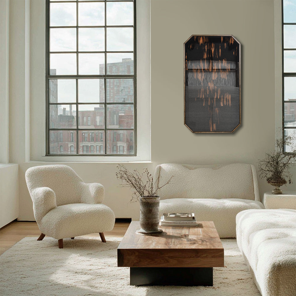 Octagonal textile art with black and orange patterns hanging on a white wall in a living room