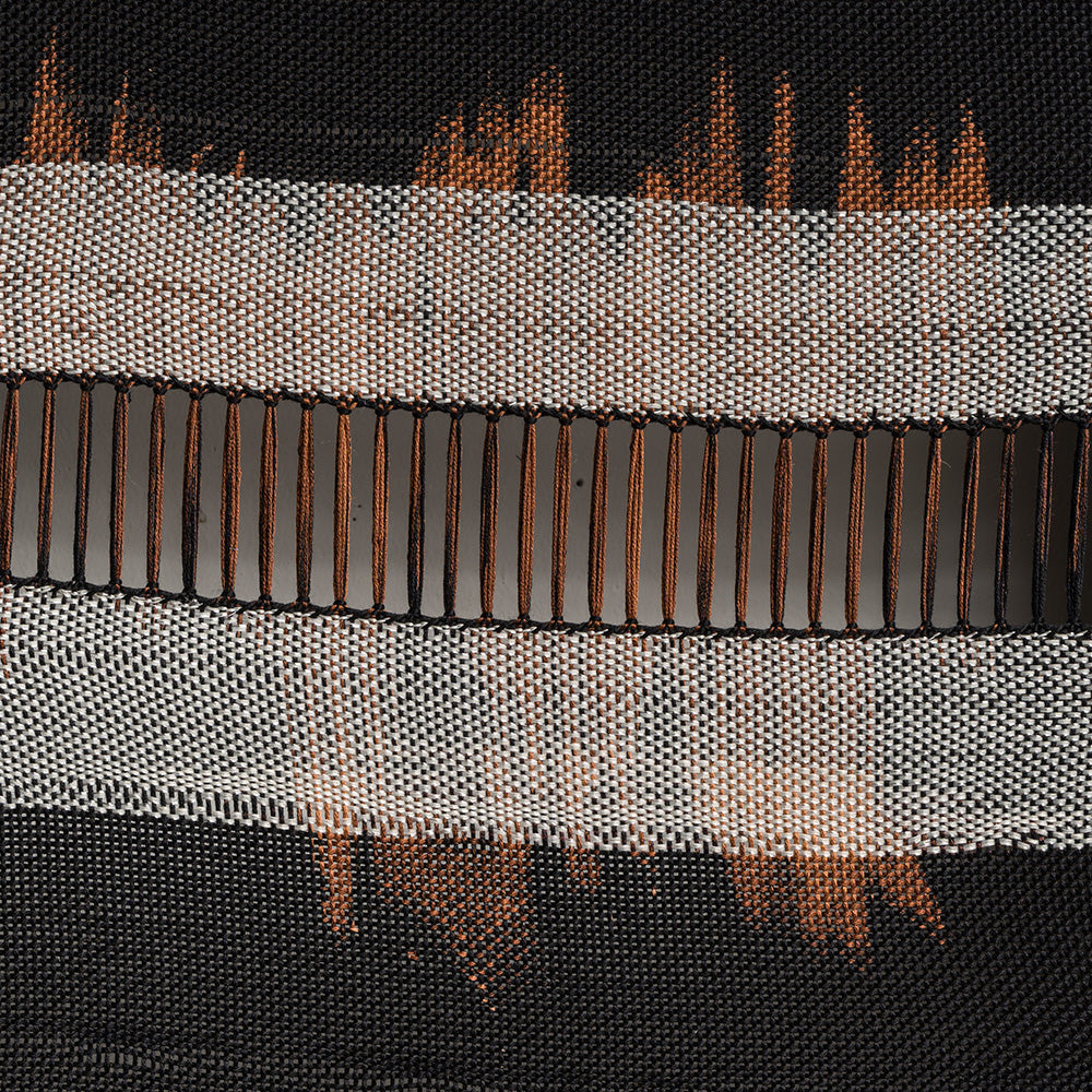 Detailed view of a black woven textile with rust-colored highlights and an open-weave horizontal panel