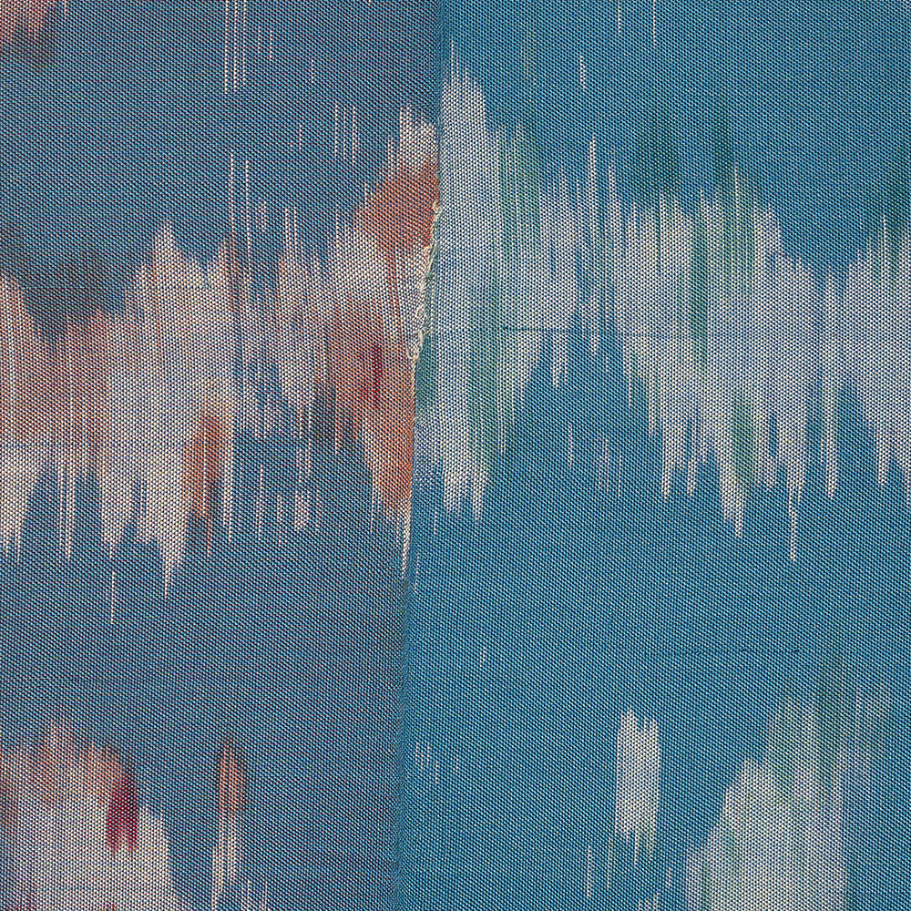 Close-up of a textile artwork revealing fine weave details and soft color gradients of sky blue teal and rust