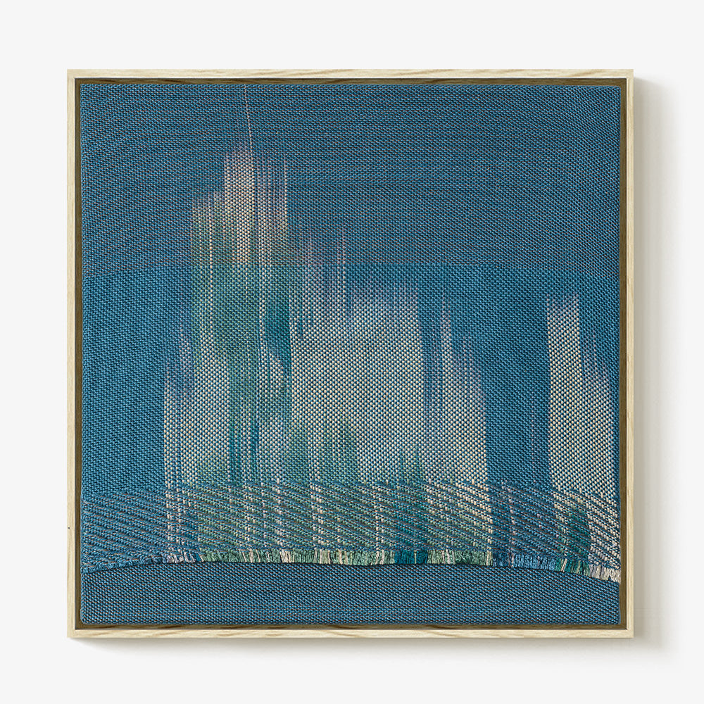 Square blue textile art piece with light-colored vertical flame-like patterns and a textured horizontal base
