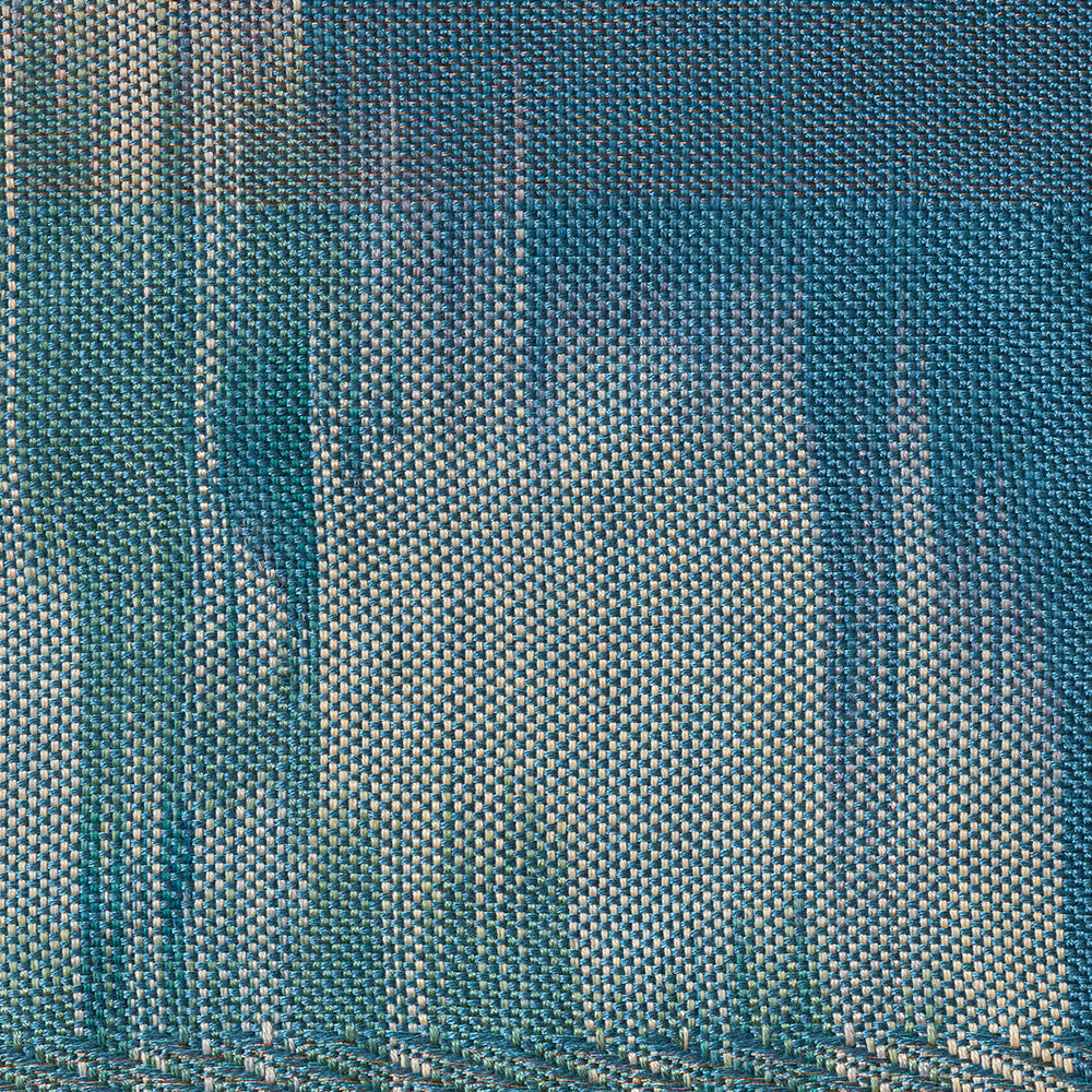 Close-up of a blue textile showing fine weave patterns and vertical streaks of light gray and teal colors