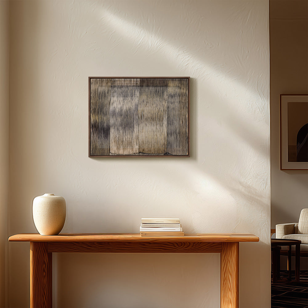 Framed abstract textile art hanging above a wooden console table in a bright minimalist room
