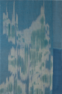 Close-up of blue textured fabric with vertical white and teal ikat-style brush-like strokes